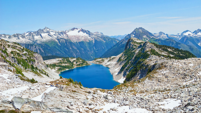 Un sommet de montagne rocheux avec un lac et une chaîne de montagnes en arrière-plan