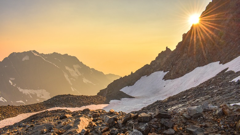 Un glacier sur un sommet de montagne avec le coucher du soleil derrière