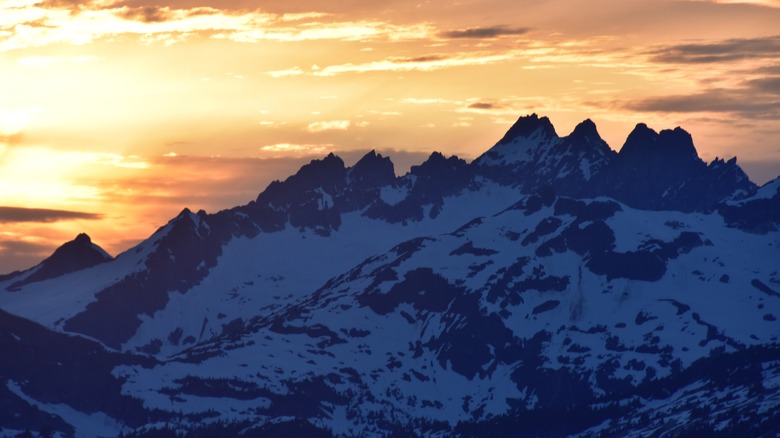 Vue aérienne d'une chaîne de montagnes escarpée couverte de neige au coucher du soleil