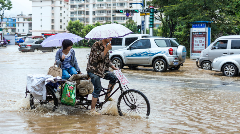 Deux personnes sur un vélo cargo pédalant dans une rue inondée