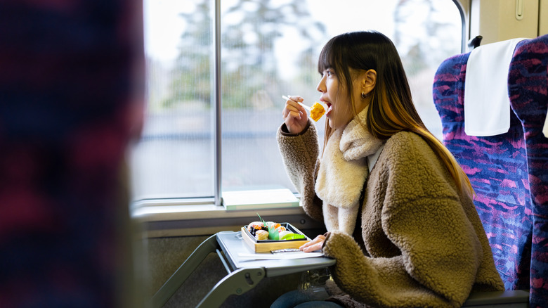 Une femme déguste un ekiben dans un train japonais