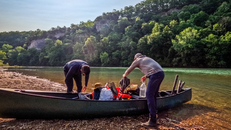 Deux hommes organisant leur équipement dans un canoë posé au sol