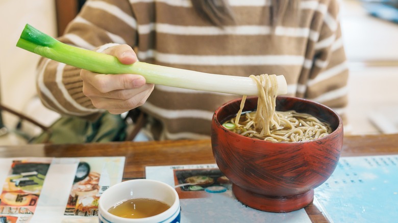 Une femme déguste un bol de negi soba à Ouchi-juku