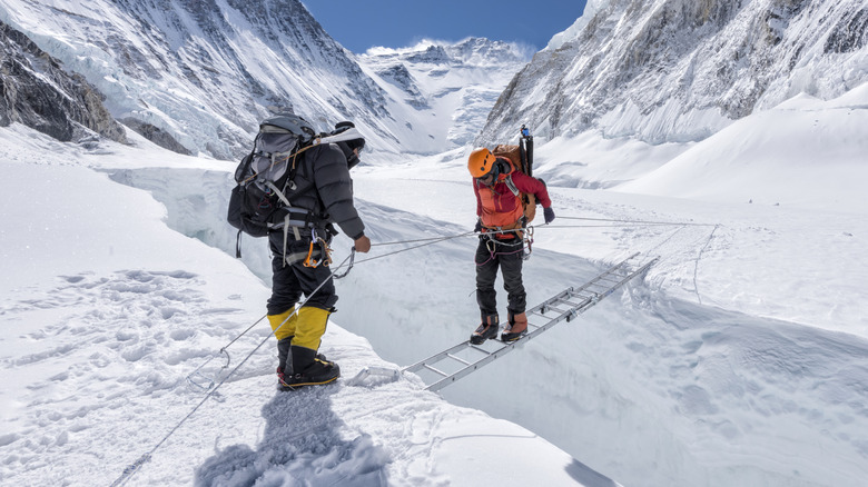 Un grimpeur traverse une crevasse sur une échelle dans le glacier du Khumbu