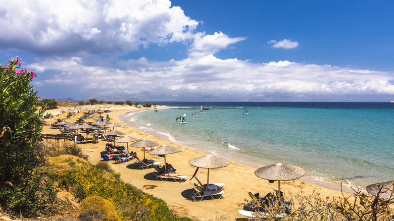 Rangées de chaises de plage et parasols au bord d'une eau turquoise en Grèce