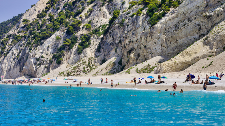 Plage de sable blanc avec falaises et eau bleue cristalline