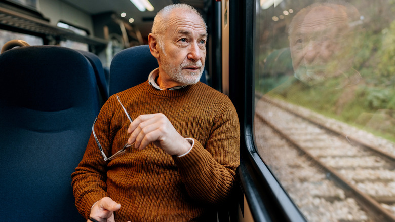 Homme âgé regardant par la fenêtre d'un train