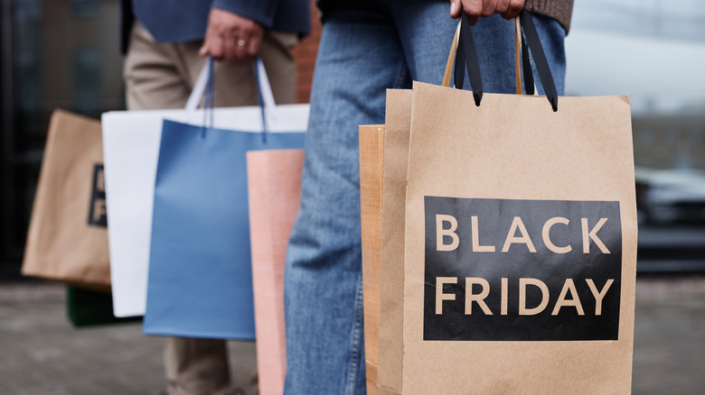 Deux personnes tenant des sacs de courses avec l'inscription Black Friday