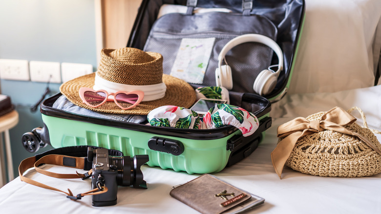 Une valise ouverte remplie d'accessoires de voyage comme un casque et des lunettes de soleil