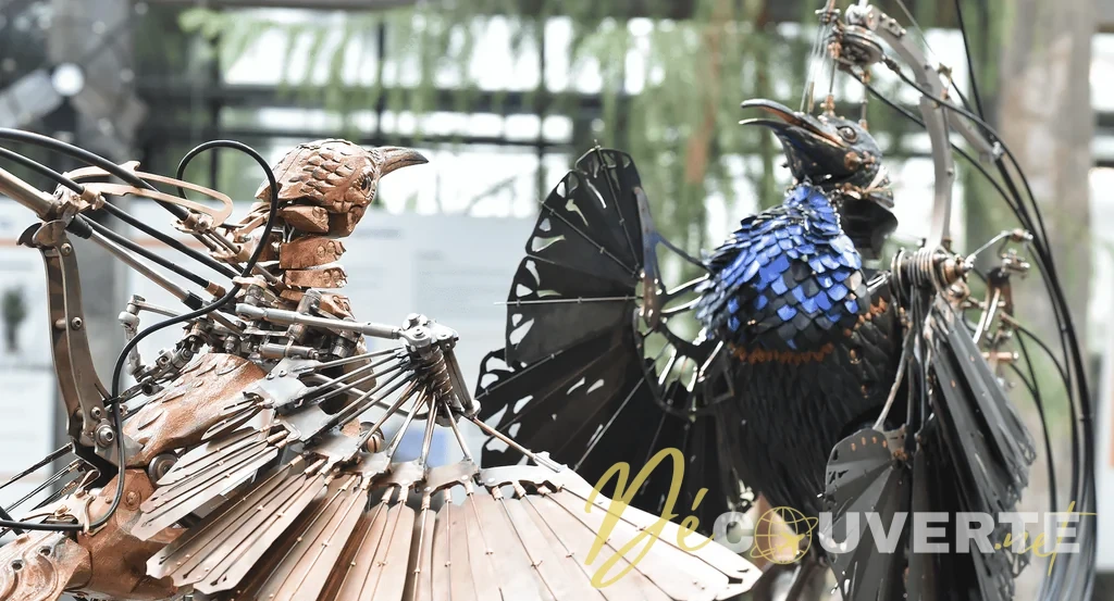 Deux oiseaux mécaniques aux ailes déployées, avec leurs articulations visibles dans la Galerie des Machines.